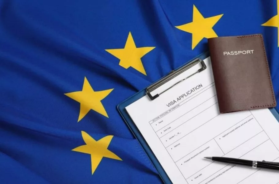 فرم درخواست ویزای شینگن همراه با پاسپورت روی پرچم اتحادیه اروپا